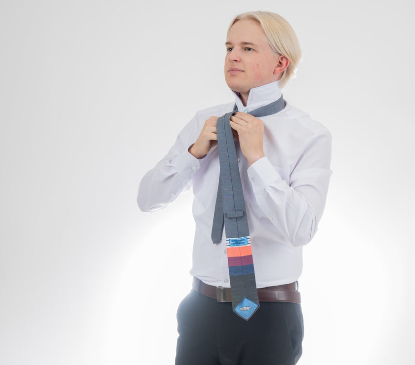 A man wearing a cool, modern necktie with thick coral, purple, and blue stripes