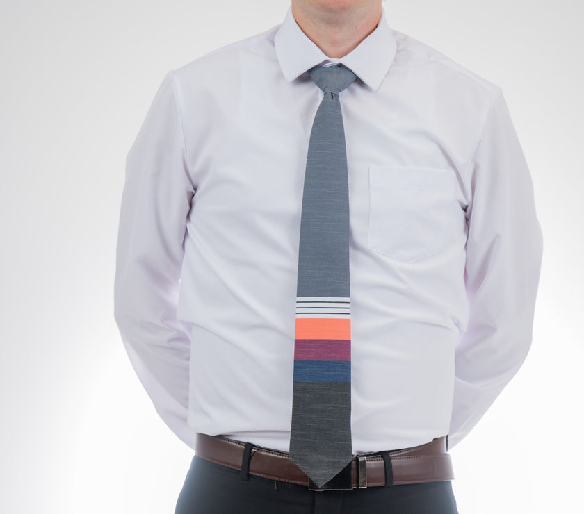 A man wearing a cool, modern necktie with thick coral, purple, and blue stripes