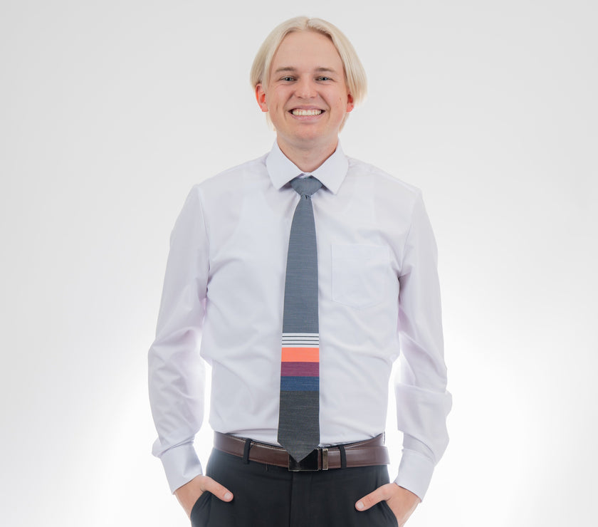 A man wearing a cool, modern necktie with thick coral, purple, and blue stripes