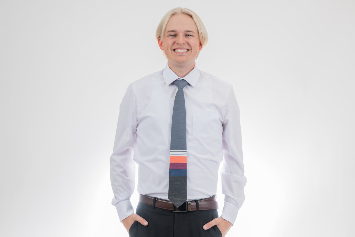 A man wearing a cool, modern necktie with thick coral, purple, and blue stripes