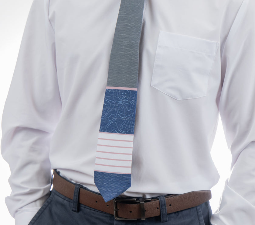 A man wearing a gray, pink, and blue necktie with stripes and topography lines pattern