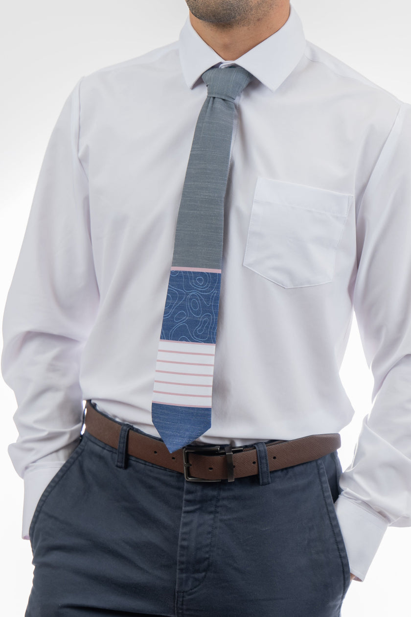 A man wearing a gray, pink, and blue necktie with stripes and topography lines pattern