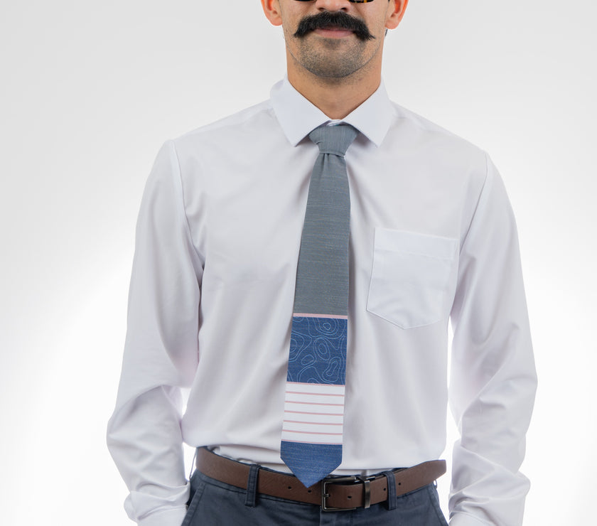 A man wearing a gray, pink, and blue necktie with stripes and topography lines pattern