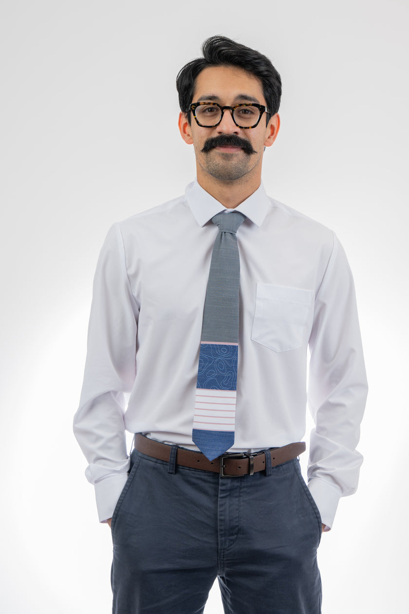 A man wearing a gray, pink, and blue necktie with stripes and topography lines pattern