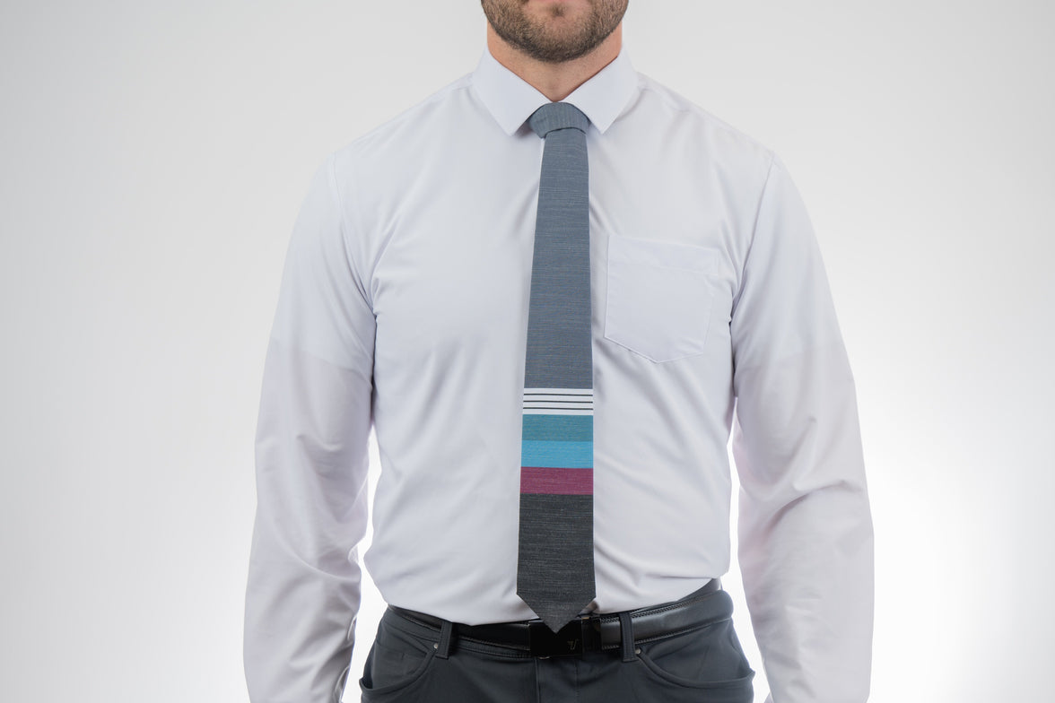 A man wearing a cool, modern necktie with thick purple, green, turquoise stripes