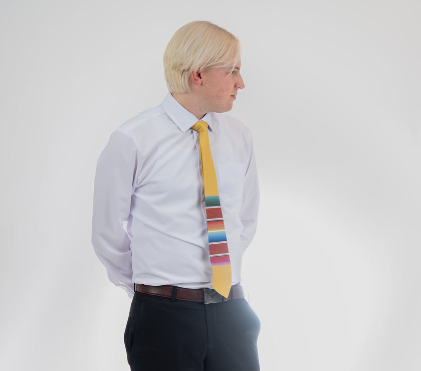 A man wearing a fun, yellow necktie with multicolored stripes in the style of a Mexican blanket