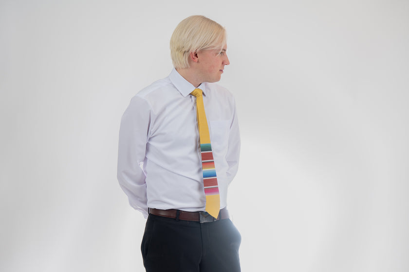 A man wearing a fun, yellow necktie with multicolored stripes in the style of a Mexican blanket