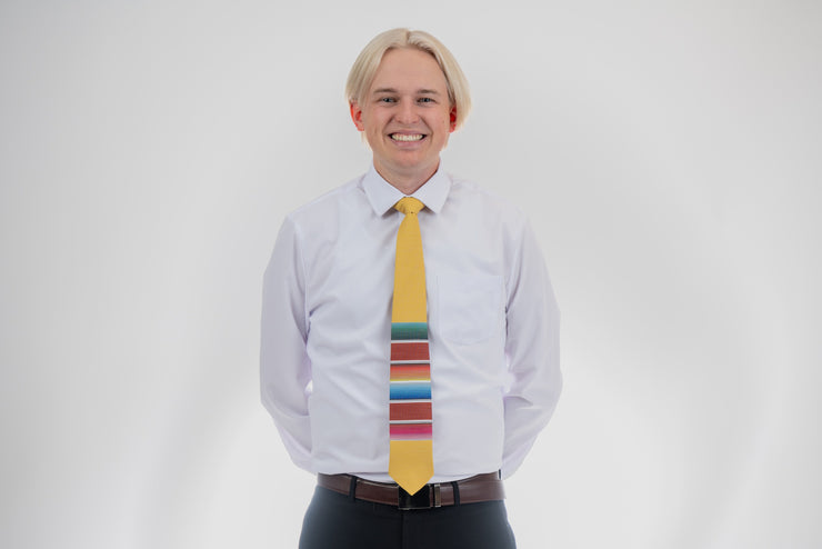 A man wearing a fun, yellow necktie with multicolored stripes in the style of a Mexican blanket