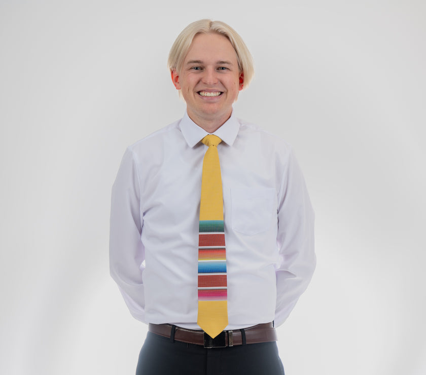 A man wearing a fun, yellow necktie with multicolored stripes in the style of a Mexican blanket