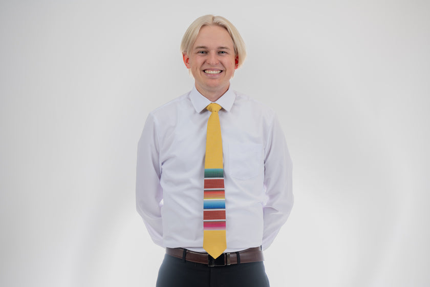 A man wearing a fun, yellow necktie with multicolored stripes in the style of a Mexican blanket