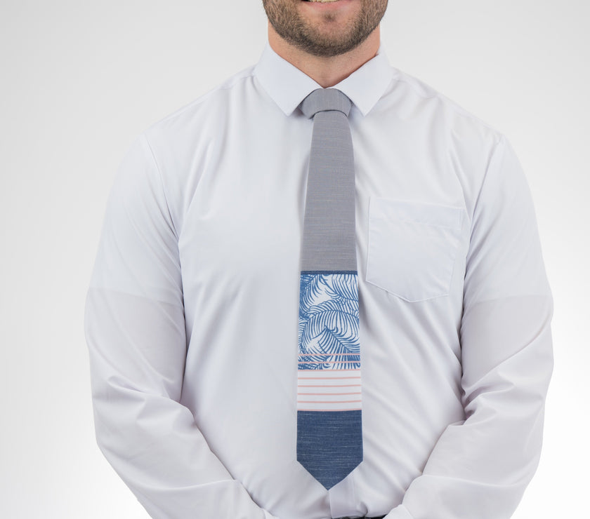 Man wearing a modern gray and blue necktie with stripes and palm leaves