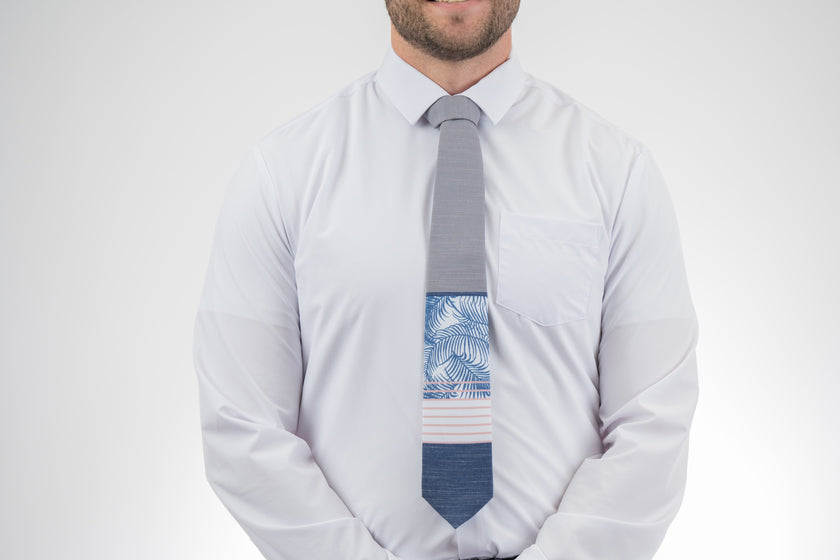 Man wearing a modern gray and blue necktie with stripes and palm leaves