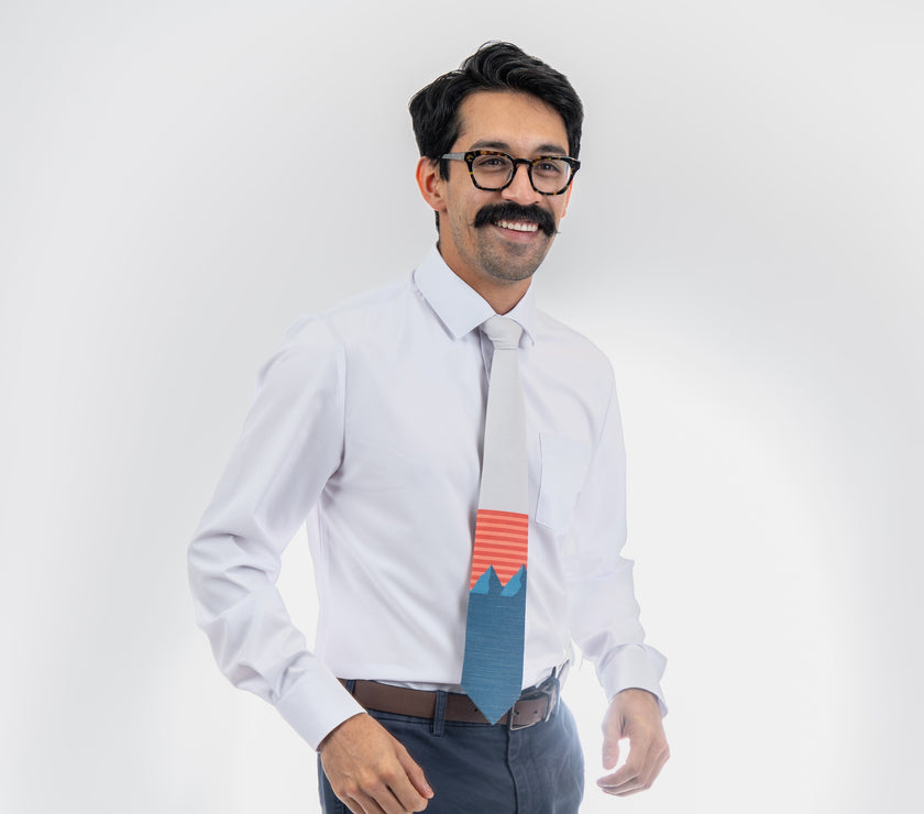 A man wearing a light gray and blue mountain tie with orange and pink stripes