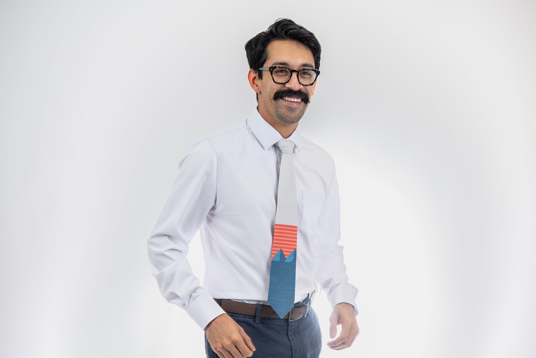 A man wearing a light gray and blue mountain tie with orange and pink stripes
