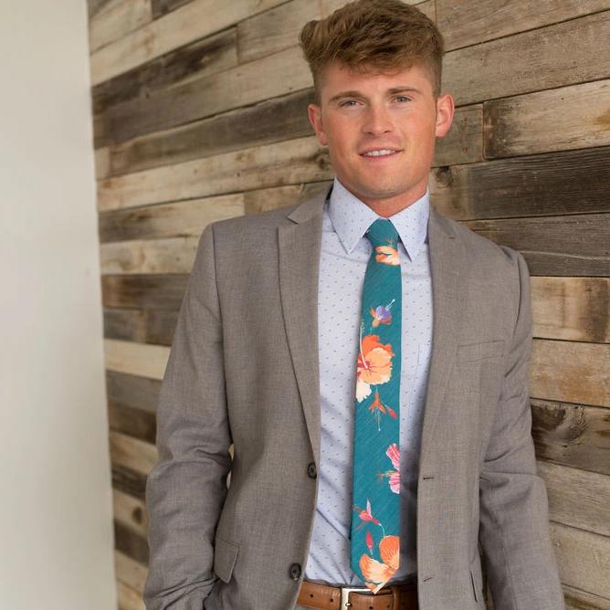 A man wearing a teal necktie with tropical floral pattern, Tie from Kator Shop in Logan, Utah – high-quality men’s accessory made for timeless style and confidence.