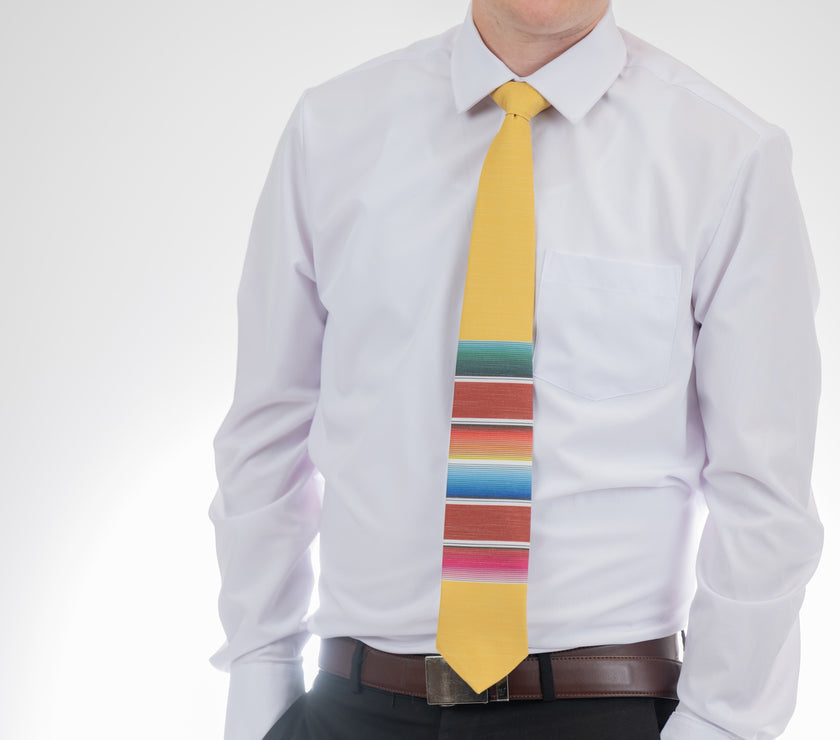 A man wearing a fun, yellow necktie with multicolored stripes in the style of a Mexican blanket