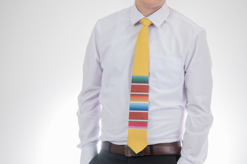 A man wearing a fun, yellow necktie with multicolored stripes in the style of a Mexican blanket