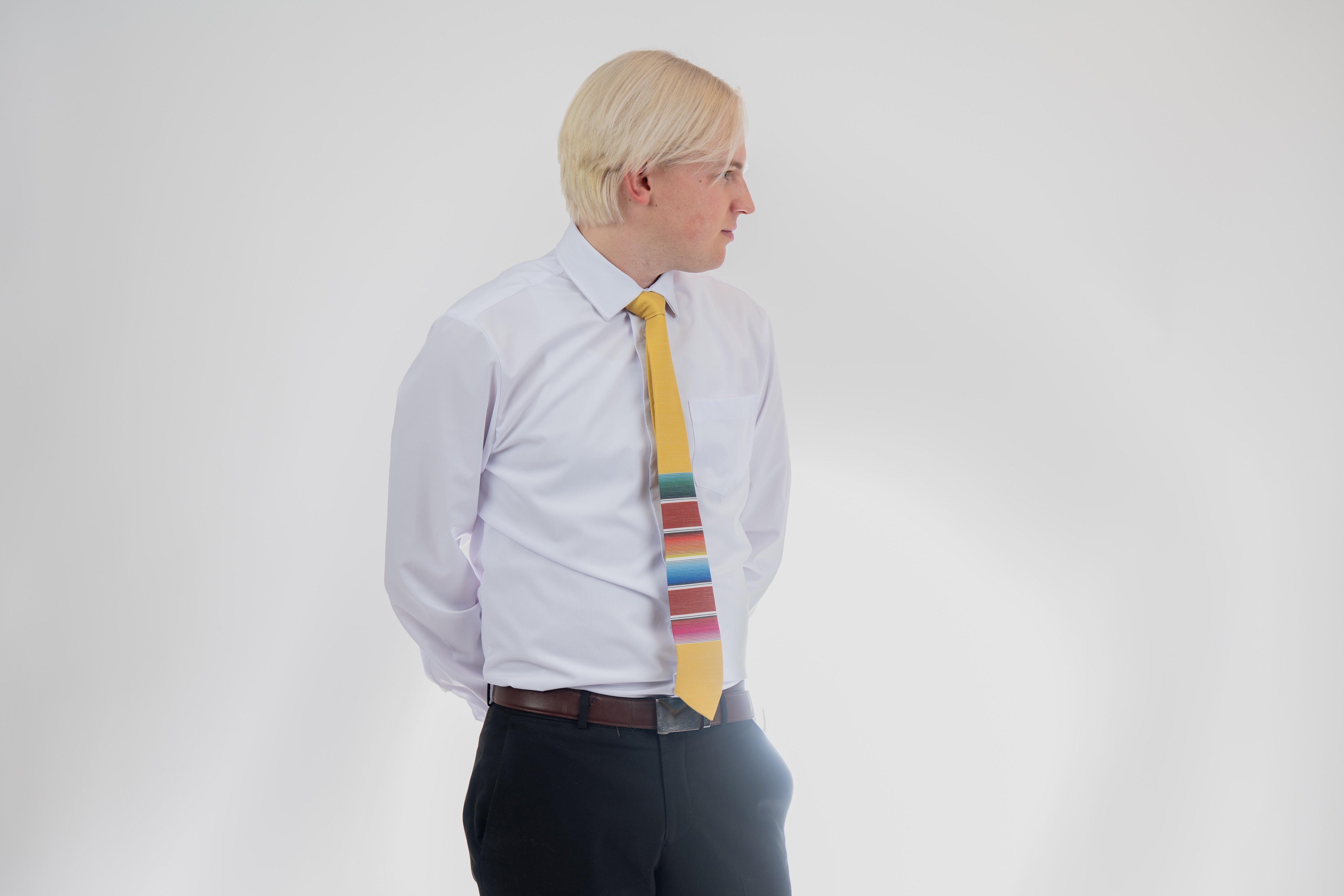 A man wearing a fun, yellow necktie with multicolored stripes in the style of a Mexican blanket. Church tie from Kator Shop in Logan, Utah — classic, respectful, and comfortable design perfect for weekly services.