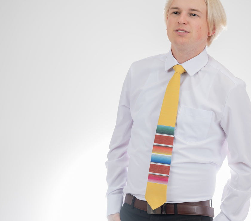 A man wearing a fun, yellow necktie with multicolored stripes in the style of a Mexican blanket