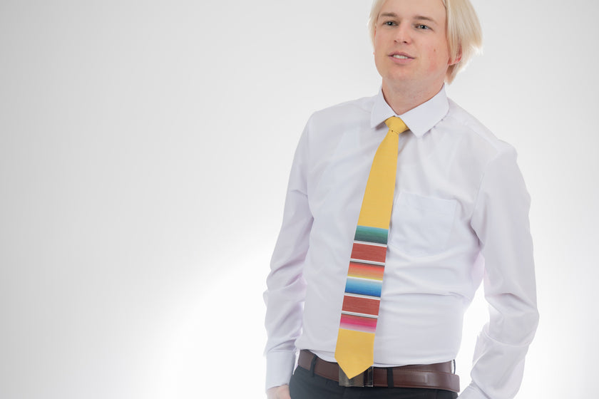 A man wearing a fun, yellow necktie with multicolored stripes in the style of a Mexican blanket