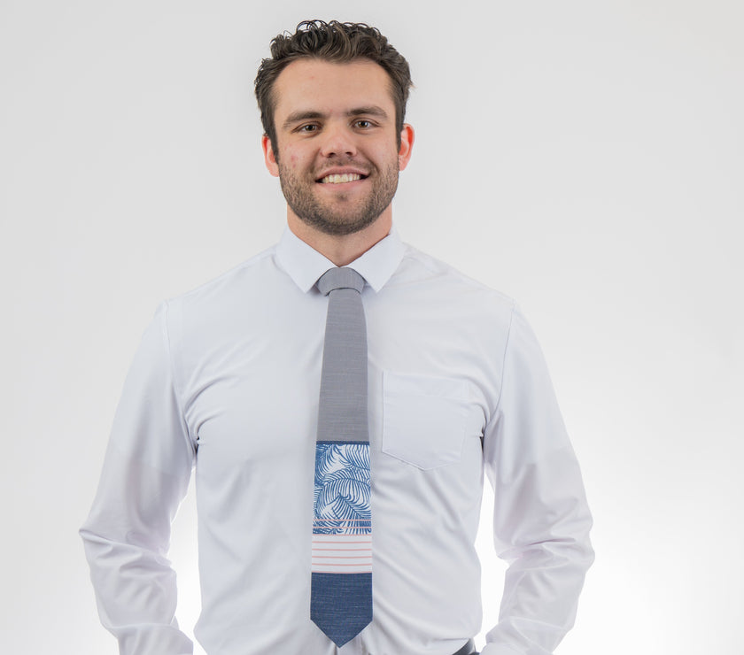 Man wearing a modern gray and blue necktie with stripes and palm leaves. Formal tie from Kator Shop Logan — refined Utah design for galas, ceremonies, and special occasions.