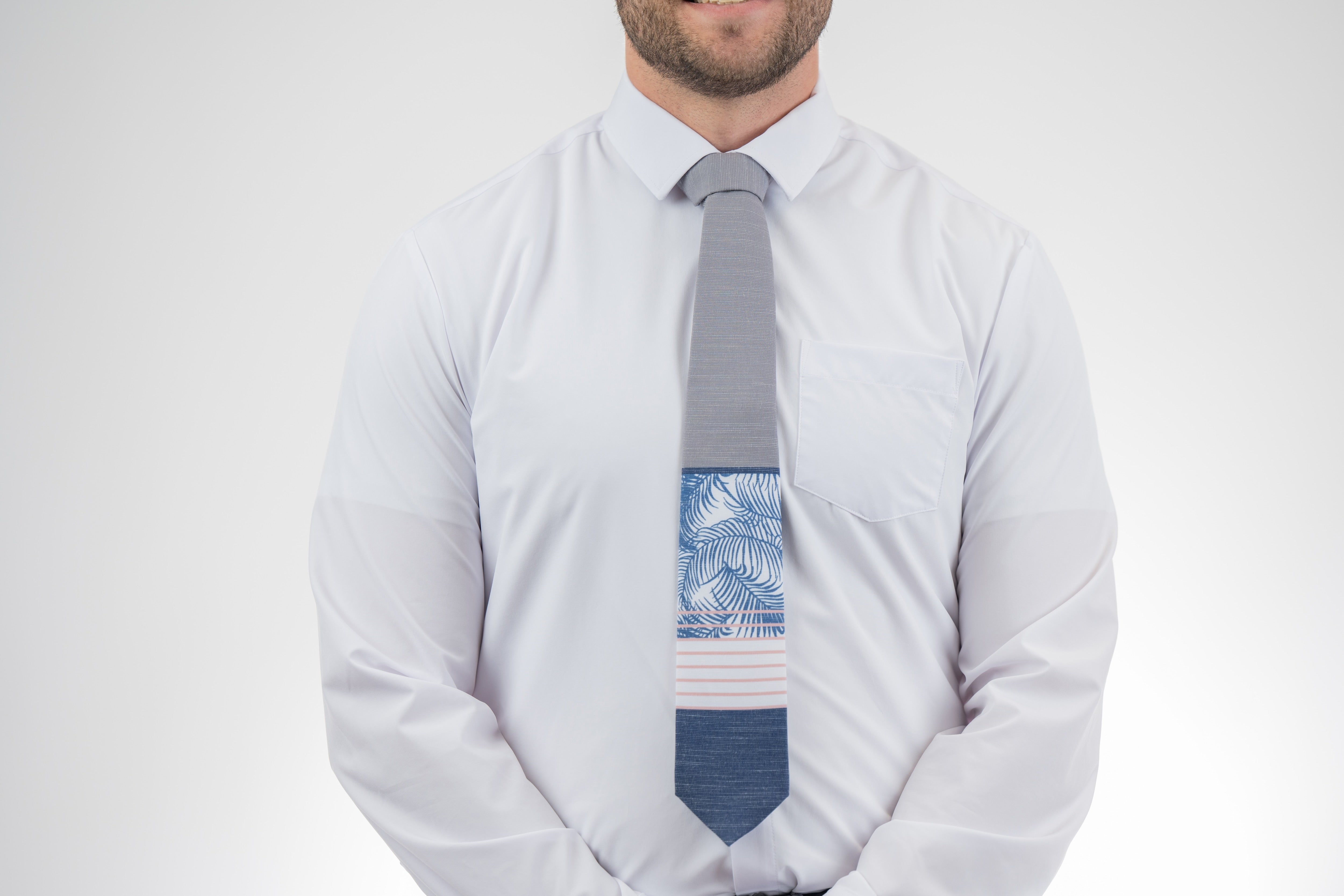Man wearing a modern gray and blue necktie with stripes and palm leaves. Premium tie from Kator Shop in Cache Valley — thoughtful Utah gift for birthdays, missions, or holidays.