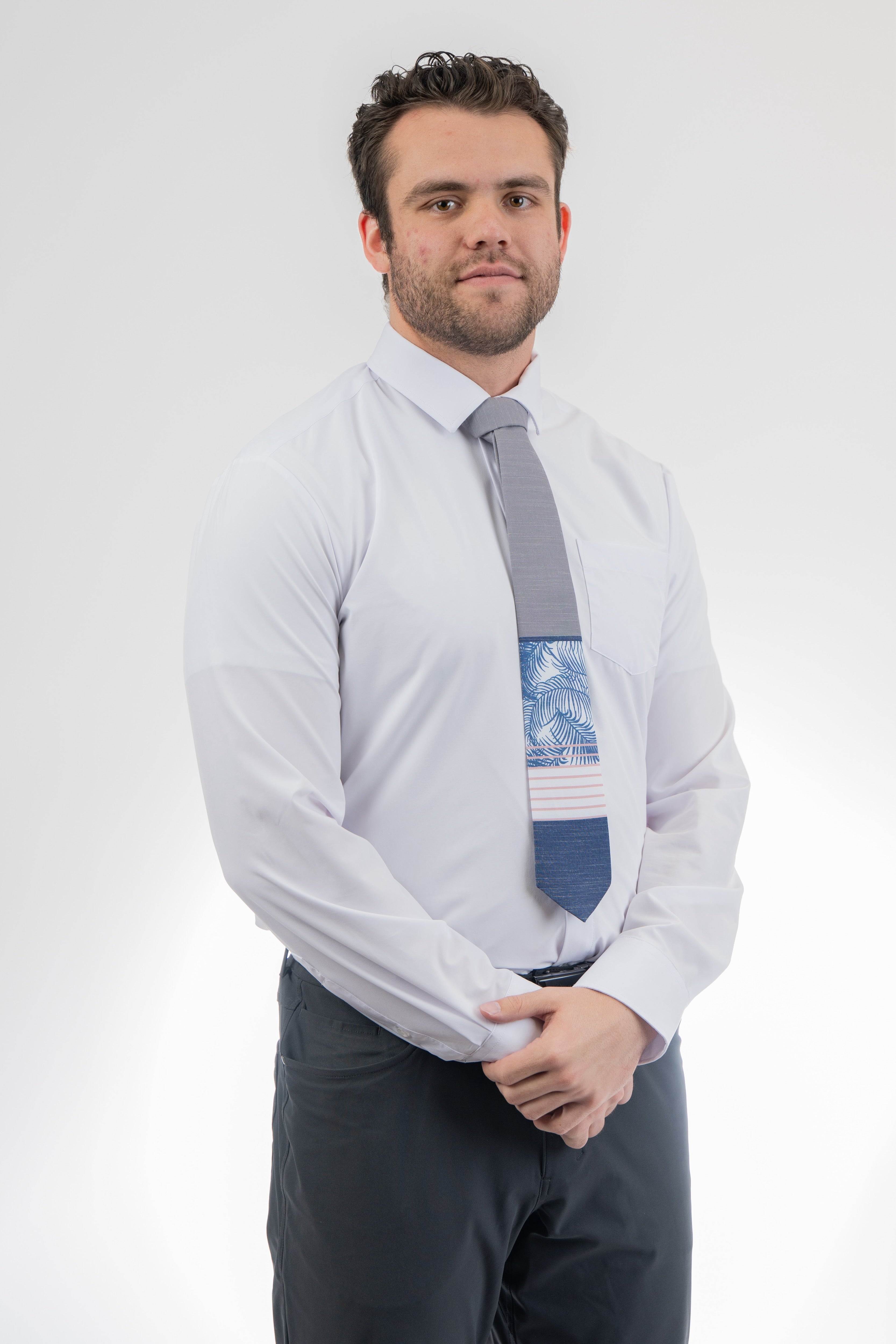 Man wearing a modern gray and blue necktie with stripes and palm leaves. Sharp prom tie from Kator Shop in Logan, Utah — bold color and luxury texture for a standout prom night look.