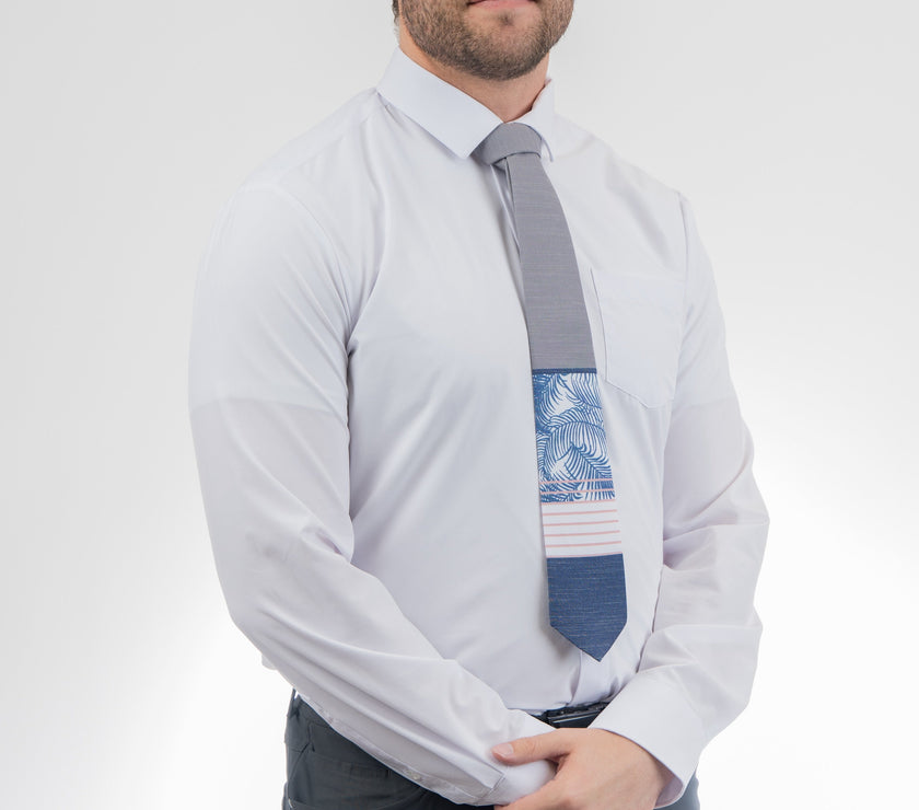 Man wearing a modern gray and blue necktie with stripes and palm leaves. Sharp prom tie from Kator Shop in Logan, Utah — bold color and luxury texture for a standout prom night look.