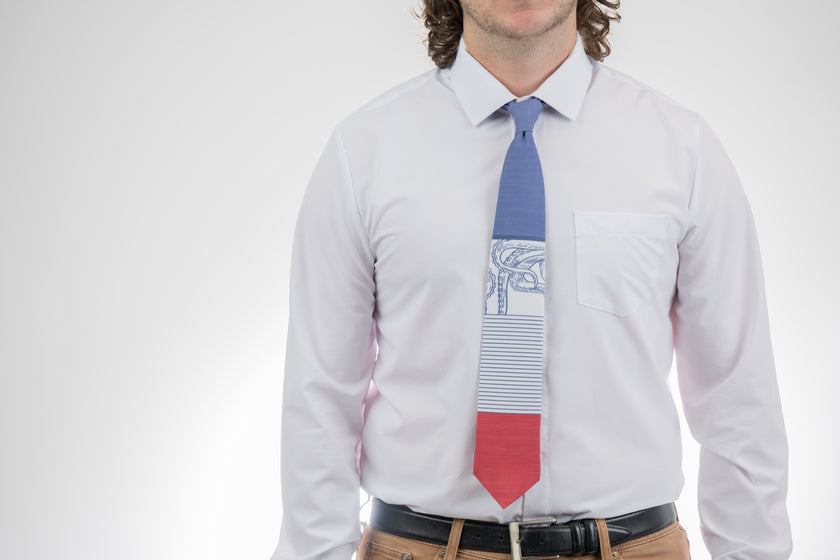A man wearing a blue, white, and red necktie with stripes and an octopus on it. Everyday tie from Kator Shop — versatile Utah menswear piece blending comfort, simplicity, and class.