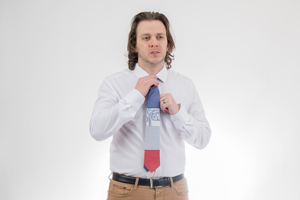 A man wearing a blue, white, and red necktie with stripes and an octopus on it. Sharp prom tie from Kator Shop in Logan, Utah — bold color and luxury texture for a standout prom night look.