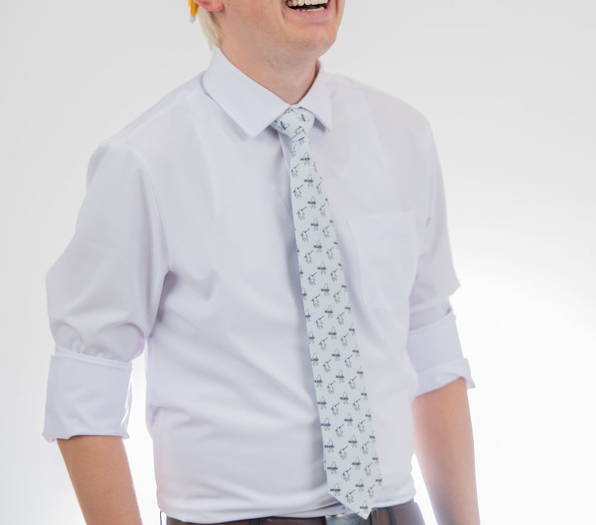 A man wearing a necktie with yetis carrying skis and snowboards, Sharp prom tie from Kator Shop in Logan, Utah — bold color and luxury texture for a standout prom night look.