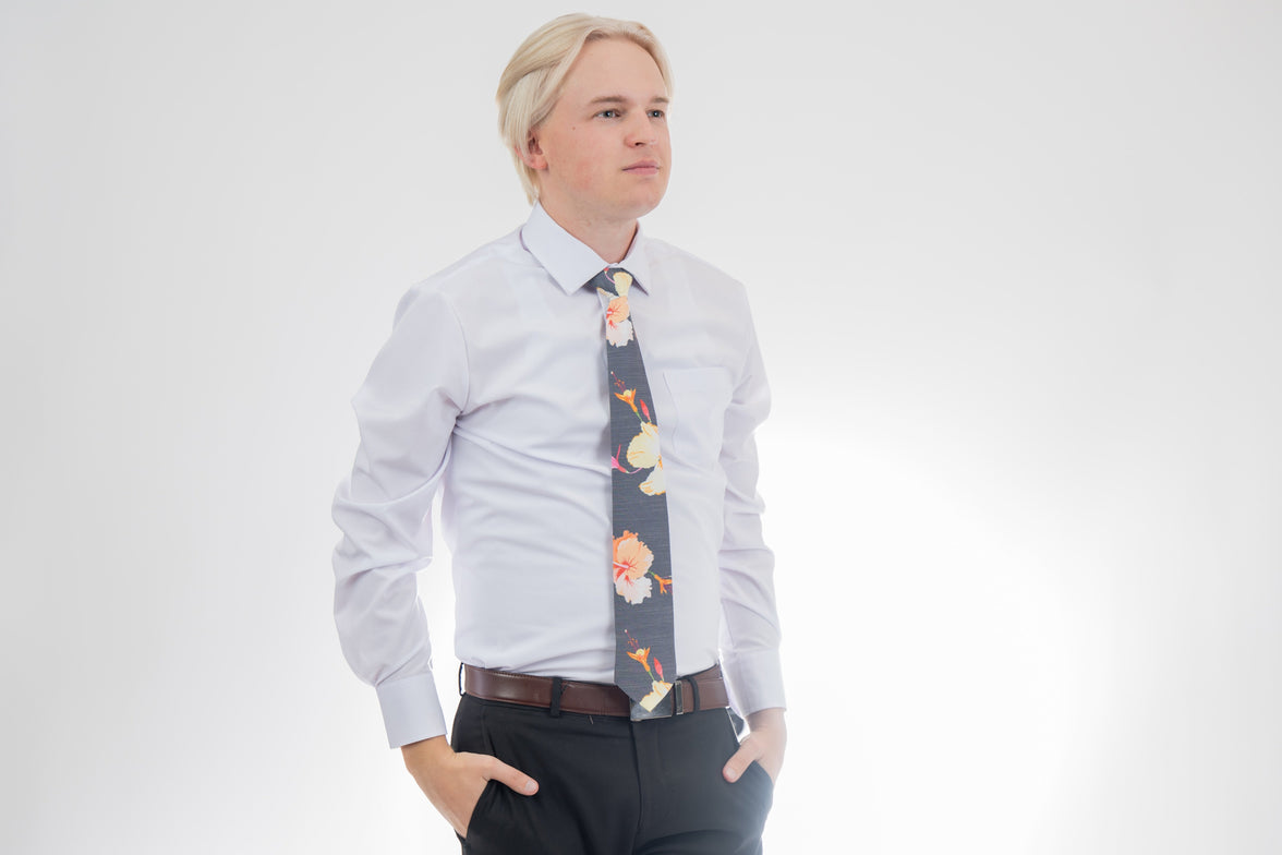 A man wearing a gray necktie with tropical floral pattern. Business tie from Kator Shop in Logan, Utah — premium material designed for confidence and all-day comfort at work.