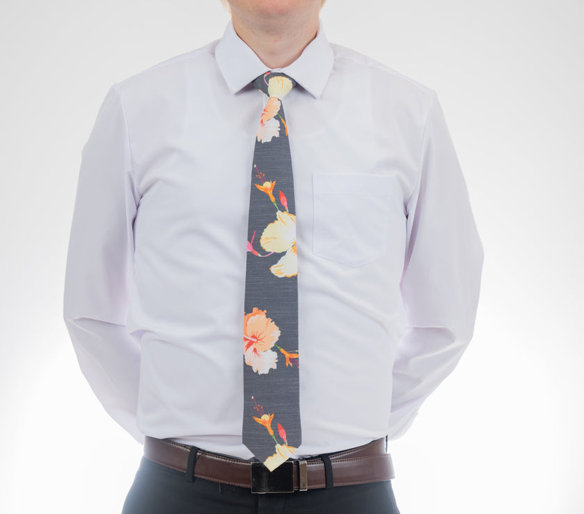 A man wearing a gray necktie with tropical floral pattern. Prom tie from Kator Shop in Logan, Utah — sleek men’s accessory for a polished, confident look on your big night.