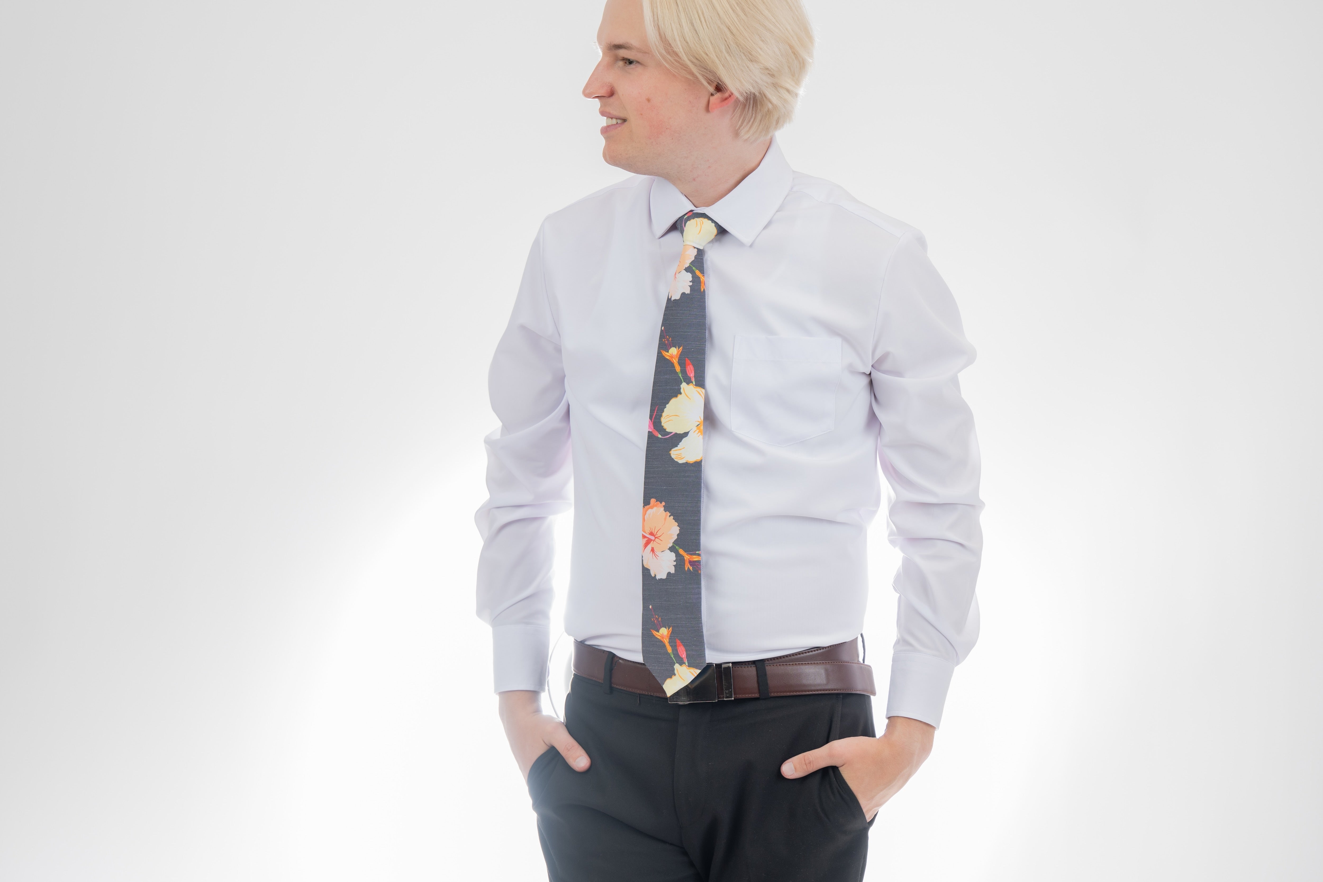 A man wearing a gray necktie with tropical floral pattern. Elegant wedding tie from Kator Shop — premium Utah craftsmanship designed to elevate any groom’s look.