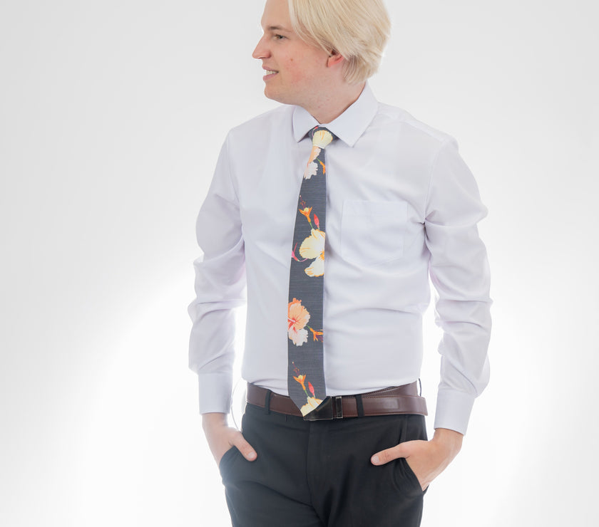 A man wearing a gray necktie with tropical floral pattern. Elegant wedding tie from Kator Shop — premium Utah craftsmanship designed to elevate any groom’s look.