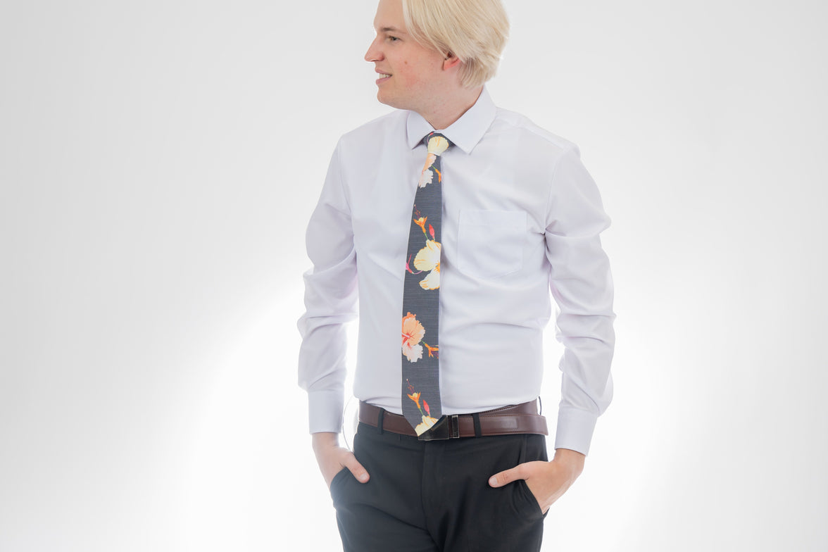 A man wearing a gray necktie with tropical floral pattern. Elegant wedding tie from Kator Shop — premium Utah craftsmanship designed to elevate any groom’s look.
